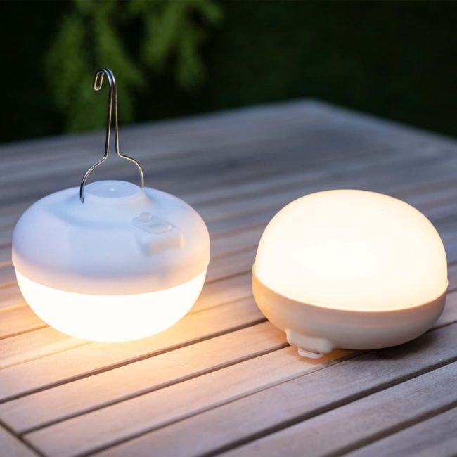 CHERRY bulb lit, one white and one beige, on a wooden table in a garden