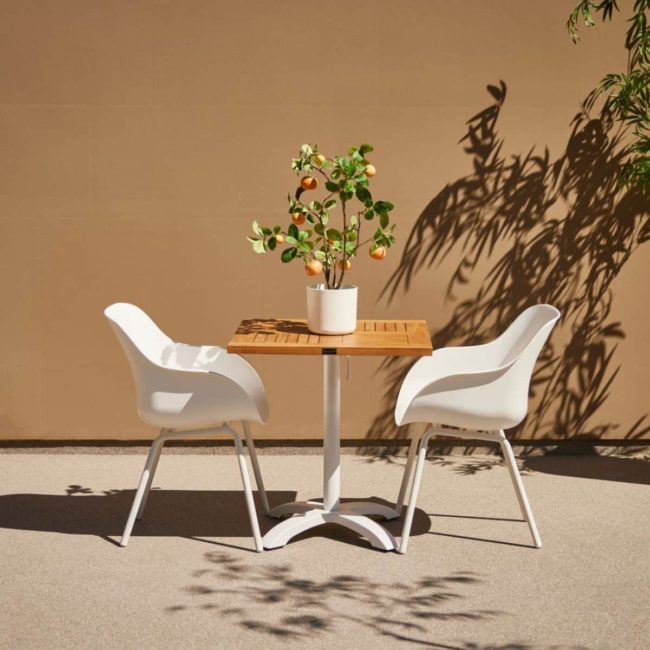 Square Bistro folding table with two white Sophie chairs, on the table a pot of kumquat oranges on a terrace in brown tones