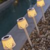 Pica solar Gretita blanco junto a piscina de noche