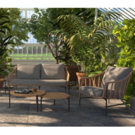 Conjunto de relax TIMOR foto ambiente en una terraza de suelo cerámico gris con mucha vegetación alrededor se ve de rente el sofá y un sillón a la derecha con dos mesas