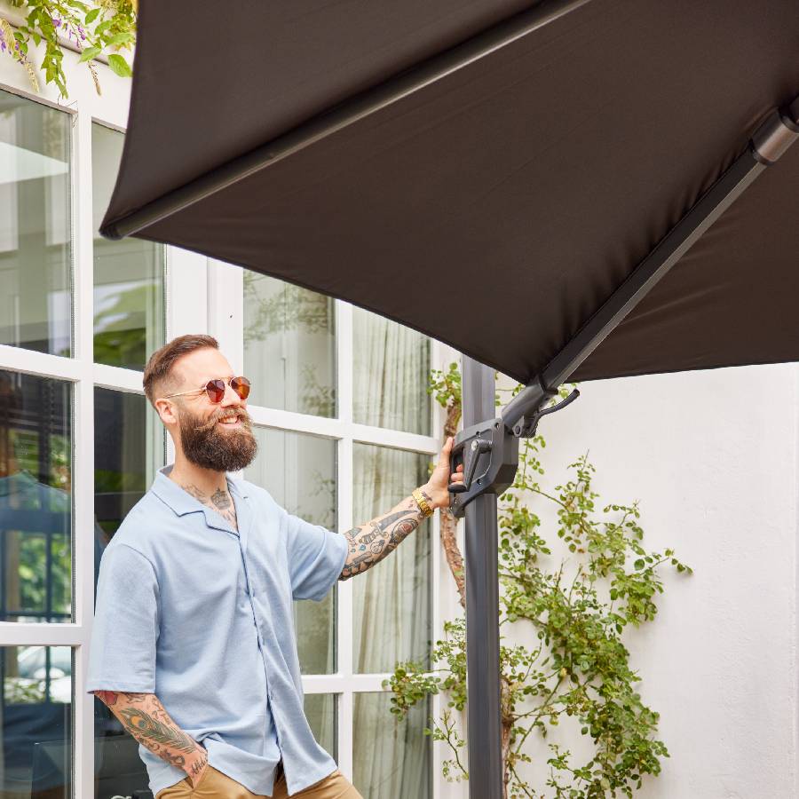 Dark Gray Shadowflex floating umbrella. Ambient photo of a man in his 30s and hipster style adjusting his inclination.