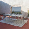Alfombra MARSANNE 240x320cm Gris - Lafuma en una terraza roja con un ventalal detrás y un conjunto de comedor encima