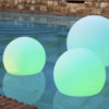 BULY Lámpara flotante solar y recargable de NewGarden se ven 3 flotando en una piscina e iluminadas en verde.