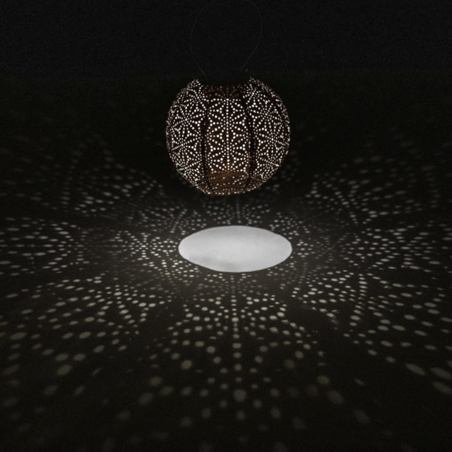 lámpara solar Ø20 SASHIKO Copper de Lumiz encendida en una habitación oscura para que se vea el reflejo que crea el patrón