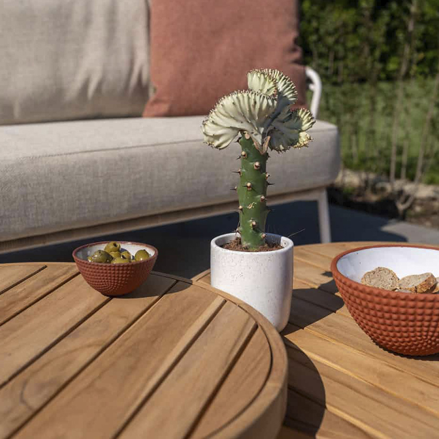 FINN center table set from 4 Seasons Outdoor. Two very attractive tables, completely made of teak. The Ø80cm table has a height of 30cm and the Ø60cm table has a height of 35cm, both with three round legs. Detail of the boards behind you can see the garden sofa DAHLIAS intense green plants.