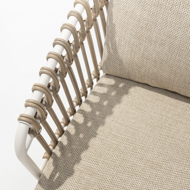 Detail of the wicker braiding on the armrest of the 4 Seasons Outoor® DALIAS Armchair with thick cushions that maximize the comfort of the seat and backrest, marbled in beige and tan beige. Armchair with tubular stainless steel structure in white, embellished with hand-woven hularo wicker around the structure in a toasted beige tone imitating traditional wicker. Right side view on white background.