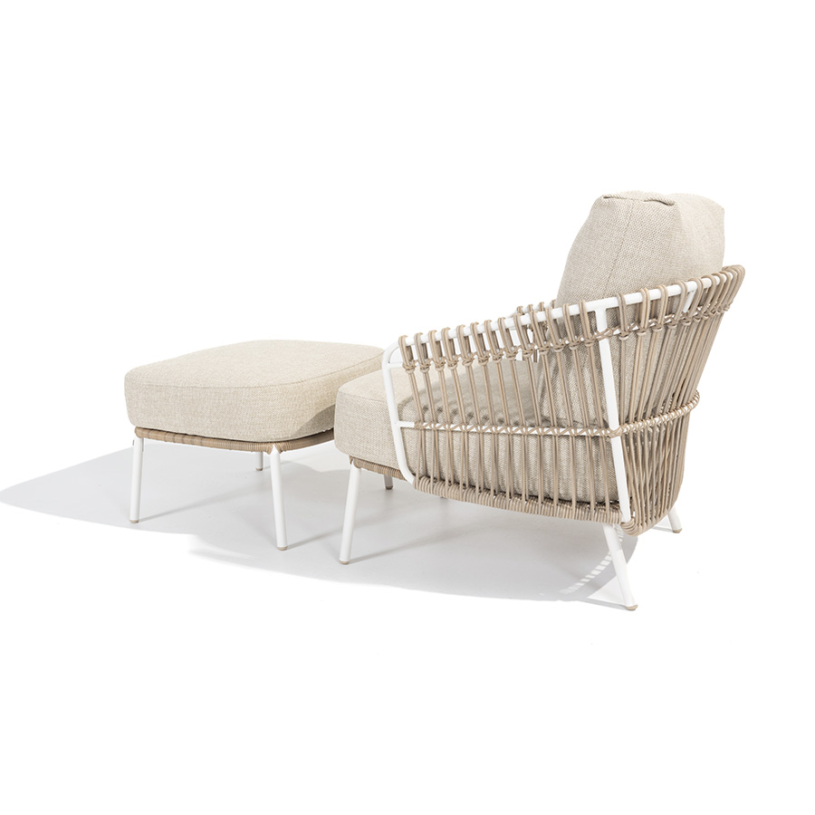 DALIAS armchair with footrest - 4 Seasons Outoor® with thick cushions that maximize the comfort of the seat and backrest, marbled in beige and tan beige. Armchair with footrest with tubular stainless steel structure in white, embellished with hand-woven hularo wicker around the structure in a toasted beige tone imitating traditional wicker. Left side view on white background.