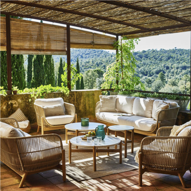 TALARA 5-seater lounge with a set of GardenLine tables on a terrace with an orange ceramic floor and a reed roof, where you can see a very green mountain and the sky