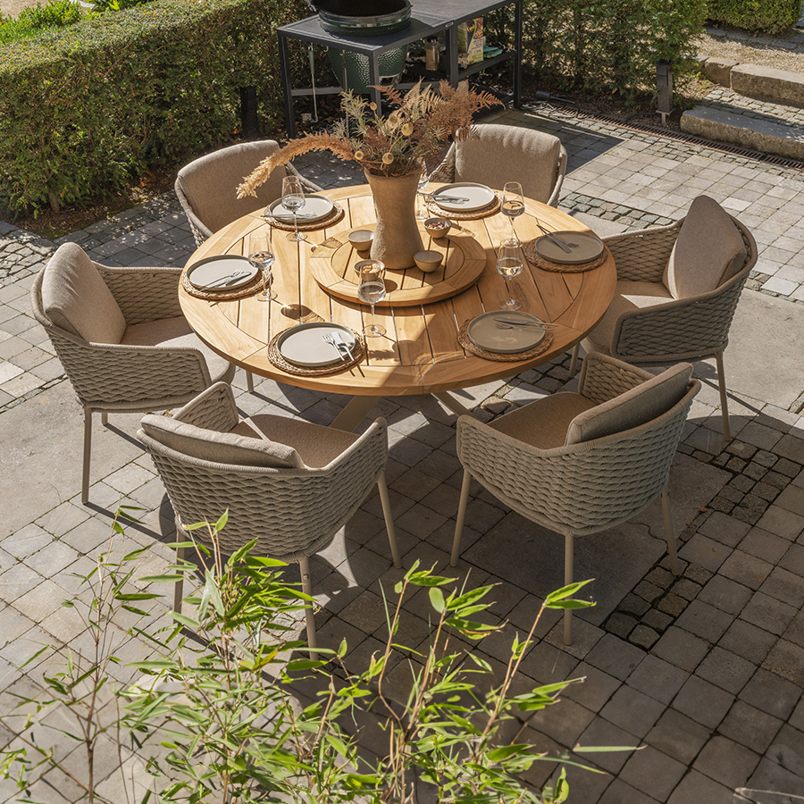 Silla jardín EROSSillón DALIAS de 4 Seasons Outoor® con cojines que maximizan la comodidad del asiento y el respaldo, jaspeados en beige y beige tostado. La Silla de jardín Eros de estructura tubular de acero inoxidable en latte o beige tostado, embellecida con la cuerda trenzada a mano alrededor de la estructura en tono beige tostado creando un patrón acolchado.