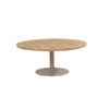 Saba Low Table by 4SO. Front view taken slightly from above to showcase the teak tabletop in a deep, intense orange-brown characteristic of this natural, FSC-certified tropical wood. Made of slats and finished with a rounded, perpendicular slat edge to create a circular shape. Its base is both original and practical: a single cylindrical central leg attached to a circular base, providing stability and strength. This base is made of aluminum and finished in a latte color (coffee with milk or toasted beige), a trending color for 2025. Buy it at De Tropen, your expert in garden and patio furniture. Front view taken slightly from above.