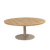 Saba Low Table by 4SO. Front view taken slightly from above to showcase the teak tabletop in a deep, intense orange-brown characteristic of this natural, FSC-certified tropical wood. Made of slats and finished with a rounded, perpendicular slat edge to create a circular shape. Its base is both original and practical: a single cylindrical central leg attached to a circular base, providing stability and strength. This base is made of aluminum and finished in a latte color (coffee with milk or toasted beige), a trending color for 2025. Buy it at De Tropen, your expert in garden and patio furniture. Front view taken slightly from above.