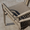 Detalle de dos sillas apiladas del respaldo, los reposabrazos y el asiento de la Silla comedor Barista latte apilable de 4 Seasons Outdoor Cómprala en De Tropen, tu experto en muebles de jardín y terraza. Foto frontal de la silla oblicua sobre fondo blanco.