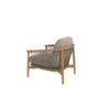 The Nora teak armchair by 4SO features an ergonomic, rounded teak frame embellished with taupe rope knotted from the armrests to the seat base, creating a signature pattern of the Nora collection. Both the legs and the frame are cylindrical and smooth. The chair includes both seat and back cushions in different shades of toasted beige. Purchase it at De Tropen, your expert in garden and patio furniture. Front view of the armchair against a white background.