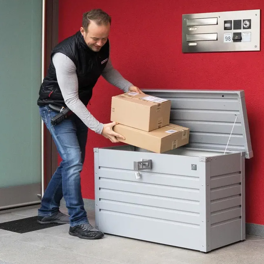 Caja para Paquetería de Biohort. Foto ambiente mensajero guardando paquetes en la caja para paquetería en plata. Encuéntralo en De Tropen, la mayor tienda de muebles de jardín de Málaga.