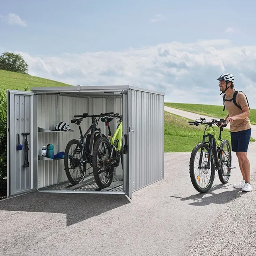 Biohort Mini Garage. Photo of an open garage setting with two bicycles and a cyclist on the right. Find it at De Tropen for the best price. Trust the largest outdoor furniture store in Malaga.