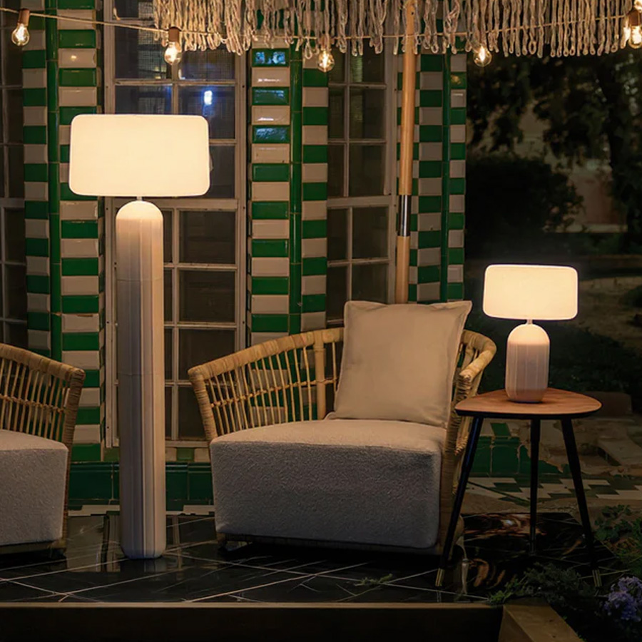 Phoebe 40 and 145 solar table lamps in white by NewGarden, lifestyle photo, one on each side of an armchair, on the right the Phoebe 40 on a side table and on the left the 145 standing. Expand your horizons with De Tropen®, come and discover the possibilities of lighting for your terrace or balcony. In the largest garden furniture store on the Costa del Sol, Málaga and Granada.