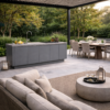 Foto ambiente de la Cocina exterior Primora Hormigón Blanca de Secenario Outdoor. Cocina exterior de acero inoxidable en gris niebla con encimera en gris hormigón, integrada en terraza mediterráneo con comedor de exterior y zona lounge. Elegante, profesional y minimalista. Cómpralo online en De Tropen la mayor tienda de muebles de jardín de Málaga.